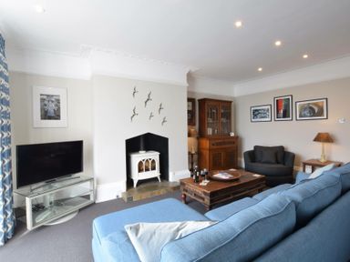 A living room with blue sofa wooden coffee table and television at Regatta Lookout in Aldeburgh