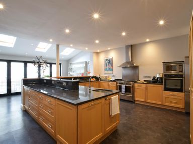 A kitchen with wooden cabinets black countertops a stove and skylights at Regatta Lookout in Aldeburgh