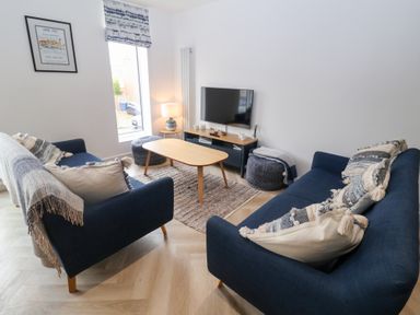 A living room with a sofa, coffee table, and television at Salt Marsh House, Southwold