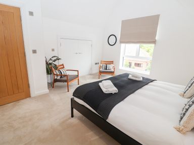 A bedroom with a bed and two chairs at Salt Marsh House, Southwold