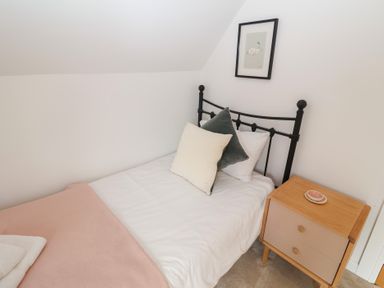 A bedroom with a bed, pillows, and a nightstand at Salt Marsh House, Southwold