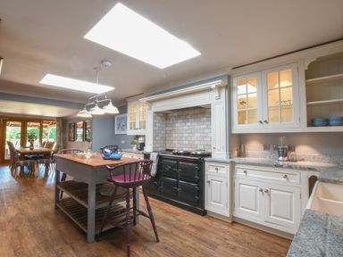 A kitchen with an island and dining table with chairs at Moat Barn in Hasketon Near Woodbridge
