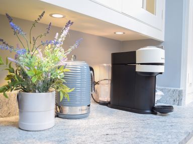 A kitchen countertop with a potted plant, an electric kettle, and a coffee machine at Moat Barn in Hasketon Near Woodbridge