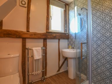 A bathroom with a toilet towel rack sink and shower with patterned tiles at Moat Barn Hasketon Near Woodbridge
