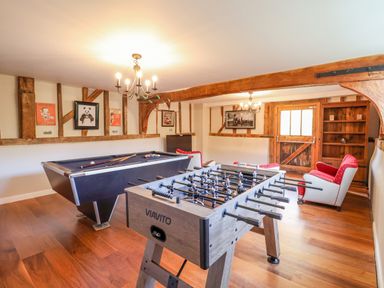 A game room with a foosball table and pool table and red armchairs at Moat Barn in Hasketon Near Woodbridge