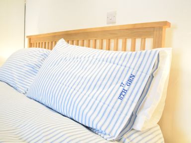 A bed with blue and white striped pillows and wooden headboard at 17 South Green Southwold