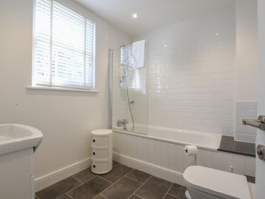 A bathroom with a bathtub shower combination toilet and small storage unit at The Gallery Blythburgh near Southwold