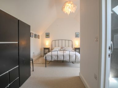 A bedroom with a metal bed frame two bedside tables with lamps and framed pictures on the walls at The Gallery, Blythburgh in Blythburgh near Southwold