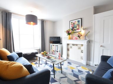 A living room with two blue sofas and a patterned rug at Driftwood Southwold