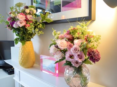 A shelf with two vases of flowers and a framed photo at Driftwood Southwold