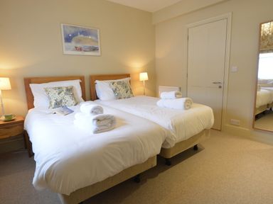 A bedroom with two single beds side by side with white bedding and rolled towels at Tamarisk Aldeburgh in Aldeburgh