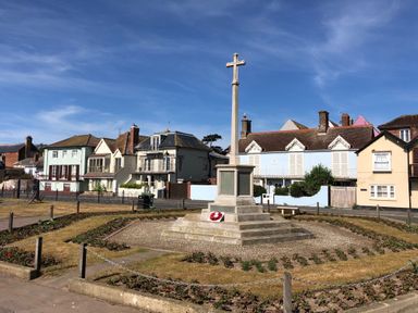 A war memorial with a cross on top in a garden surrounded by houses at Tamarisk Aldeburgh in Aldeburgh