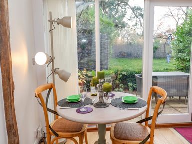 A dining area with a round table set for two with green candles and view of garden at The Bothy at Snape Hall in Snape Suffolk