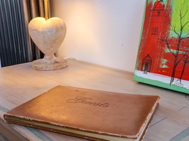 A wooden table with a heart-shaped lamp a guestbook and a painting at The Bothy at Snape Hall in Snape Suffolk