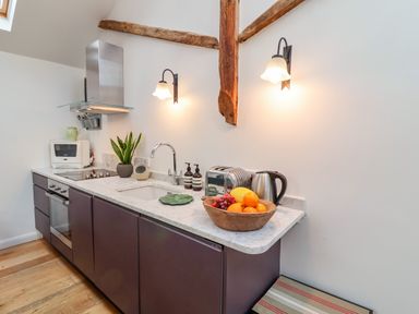 A kitchen counter with a sink toaster kettle and fruit bowl at The Bothy at Snape Hall in Snape Suffolk