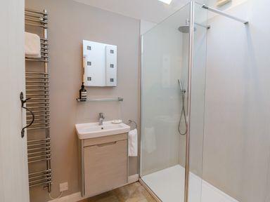 A bathroom with a glass shower enclosure a sink with a cabinet a towel rack and mirror at The Bothy at Snape Hall in Snape Suffolk