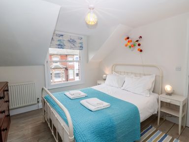 A bedroom with a double bed with blue bedspread and two bedside tables with lamps at Osprey in Southwold
