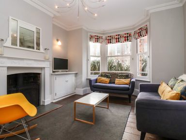 A living room with sofas a coffee table a fireplace and armchair at Kestrel in Southwold