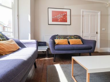 A living room with two blue sofas with cushions a white coffee table and a framed picture on the wall at Kestrel in Southwold