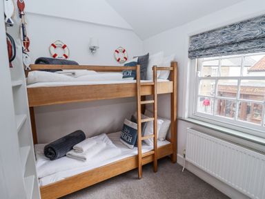 A bedroom with wooden bunk beds near a window and nautical decor at Dolphin Cottage Southwold