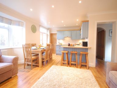A kitchen and dining area with wooden furniture and blue cabinets at Garden Cottage Southwold