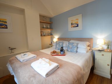 A bedroom with a double bed two bedside tables lamps and towels on the bed at Garden Cottage Southwold