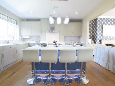 A kitchen with a central island and four white bar stools at St Marys View Southwold