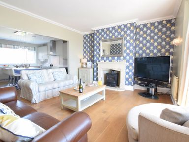 A living room with sofas coffee table fireplace TV and open kitchen at St Marys View Southwold