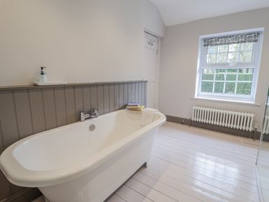 A bathroom with a bathtub and window at Fig Cottage, Pettistree Near Woodbridge
