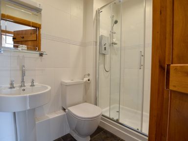 A bathroom with a sink a toilet and a shower with glass doors at Three Chantry Barns Orford