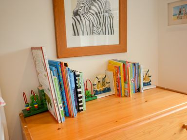 A wooden dresser with children's books and bookends under a framed zebra picture at Three Chantry Barns Orford