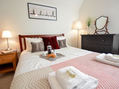 A bedroom with a bed with pillows and a tray with croissants and coffee on it at Three Chantry Barns Orford
