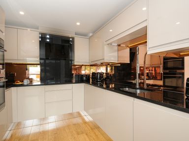 A kitchen with glossy cabinets black countertops double sink and built in appliances at Bluebell Retreat in Lostwithiel