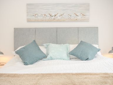 A bed with three pillows and a painting of birds above the headboard at Bluebell Retreat in Lostwithiel