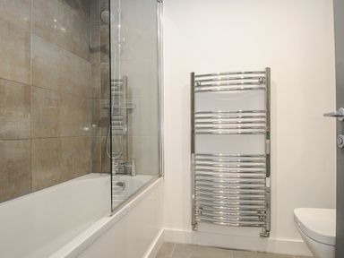 A bathroom with a bathtub shower and towel radiator at Bluebell Retreat in Lostwithiel