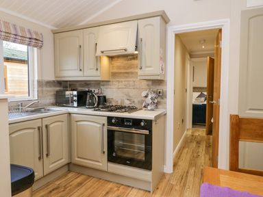A kitchen with beige cabinets and wooden floor at 8 Woodlands in Water Yeat Coniston Water