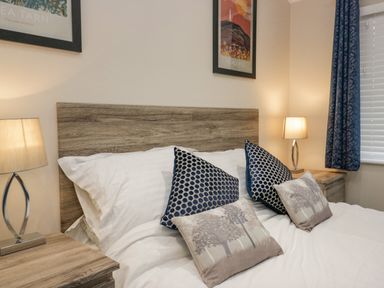 A bedroom with a wooden bed frame two bedside tables with lamps and pillows on the bed at 8 Woodlands Water Yeat Coniston Water