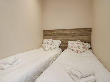 A bedroom with two single beds with white linens and floral pillows at 8 Woodlands in Water Yeat Coniston Water