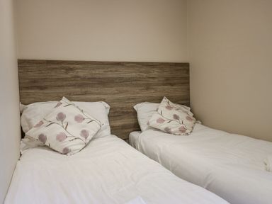 A bedroom with two single beds with white bedding and floral pillows at 8 Woodlands in Water Yeat Coniston Water