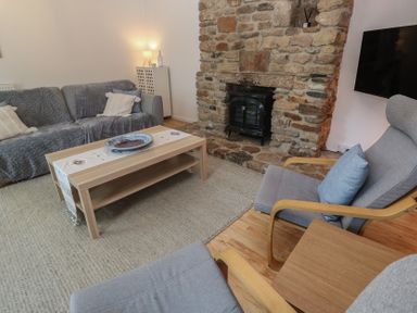 A living room with a fireplace and seating at Candle Croft near Tolgus Mount
