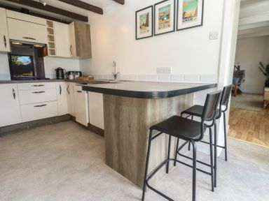 A kitchen with a bar counter and stools at Candle Croft in Tolgus Mount near Redruth