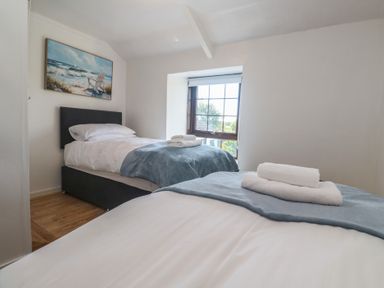 A bedroom with two single beds and a window at Candle Croft in Tolgus Mount near Redruth