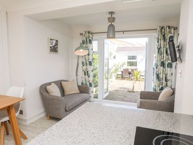 A small living area with two gray chairs and a floor lamp next to glass doors opening to a patio at Bryntirion in Moelfre
