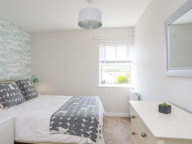 A bedroom with a double bed and patterned pillows and duvet at Bryntirion in Moelfre