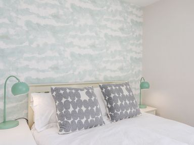 A bedroom with a bed with patterned cushions and bedside tables with lamps at Bryntirion in Moelfre