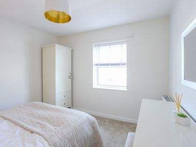 A bedroom with a bed a wardrobe a window a desk and a ceiling light at Bryntirion in Moelfre