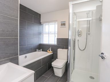 A bathroom with a bathtub a toilet a shower and a window at Bryntirion in Moelfre