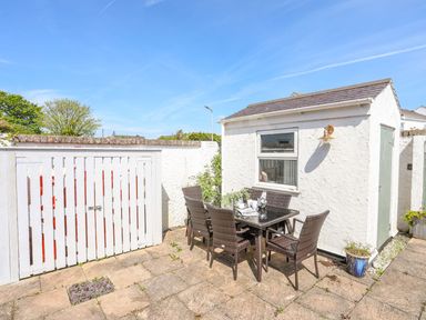An outdoor patio with a table and chairs next to a white building at Bryntirion in Moelfre