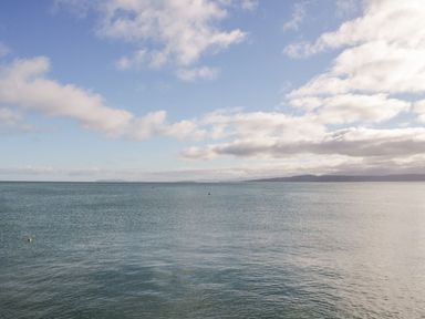 An ocean view with distant hills under a partly cloudy sky at Bryntirion in Moelfre