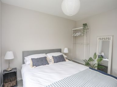 A bedroom with a bed pillows lamps mirror plant and clothes rack at Watlands in Mynytho near Abersoch